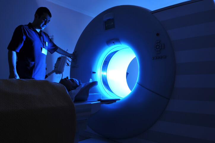patient entering mri machine in dark room with aid of technician patient entering mri machine in dark room with aid of technician