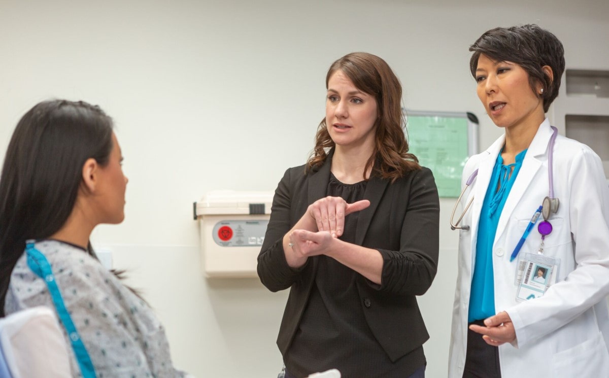 An interpreter working with a patient in a medical setting An interpreter working with a patient in a medical setting