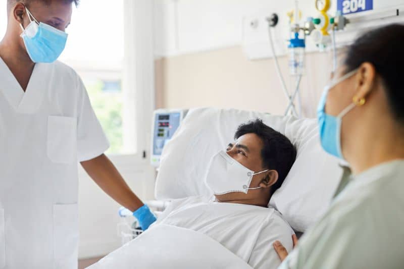 doctors consoling patient lying in bed doctors consoling patient lying in bed