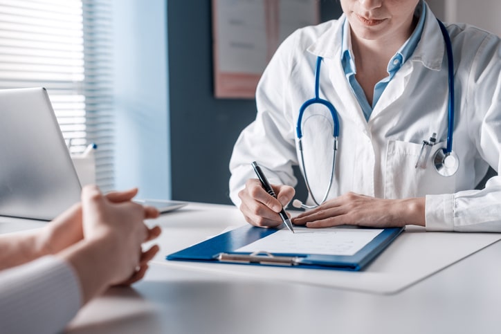 Clinicians speaking and using a laptop while sitting at a table Clinicians speaking and using a laptop while sitting at a table