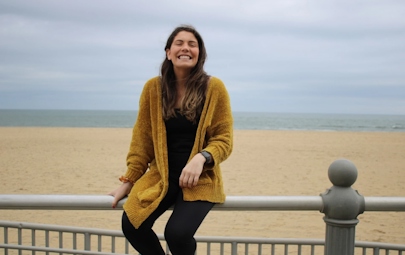 Woman smiling while sitting on a railing near a beach Woman smiling while sitting on a railing near a beach