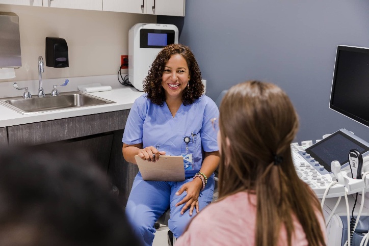 an OB/GYN holding a clipboard and smiling at a patient an OB/GYN holding a clipboard and smiling at a patient