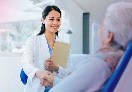 Female physician with clipboard holding patient's hand Female physician with clipboard holding patient's hand